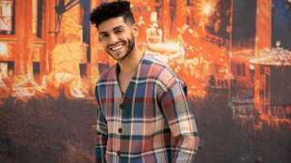 Mena Massoud | Aladdin actor Mena Massoud smiling against a colourful wall