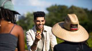 Mena Massoud | Aladdin actor Mena Massoud holding a tomato in a field