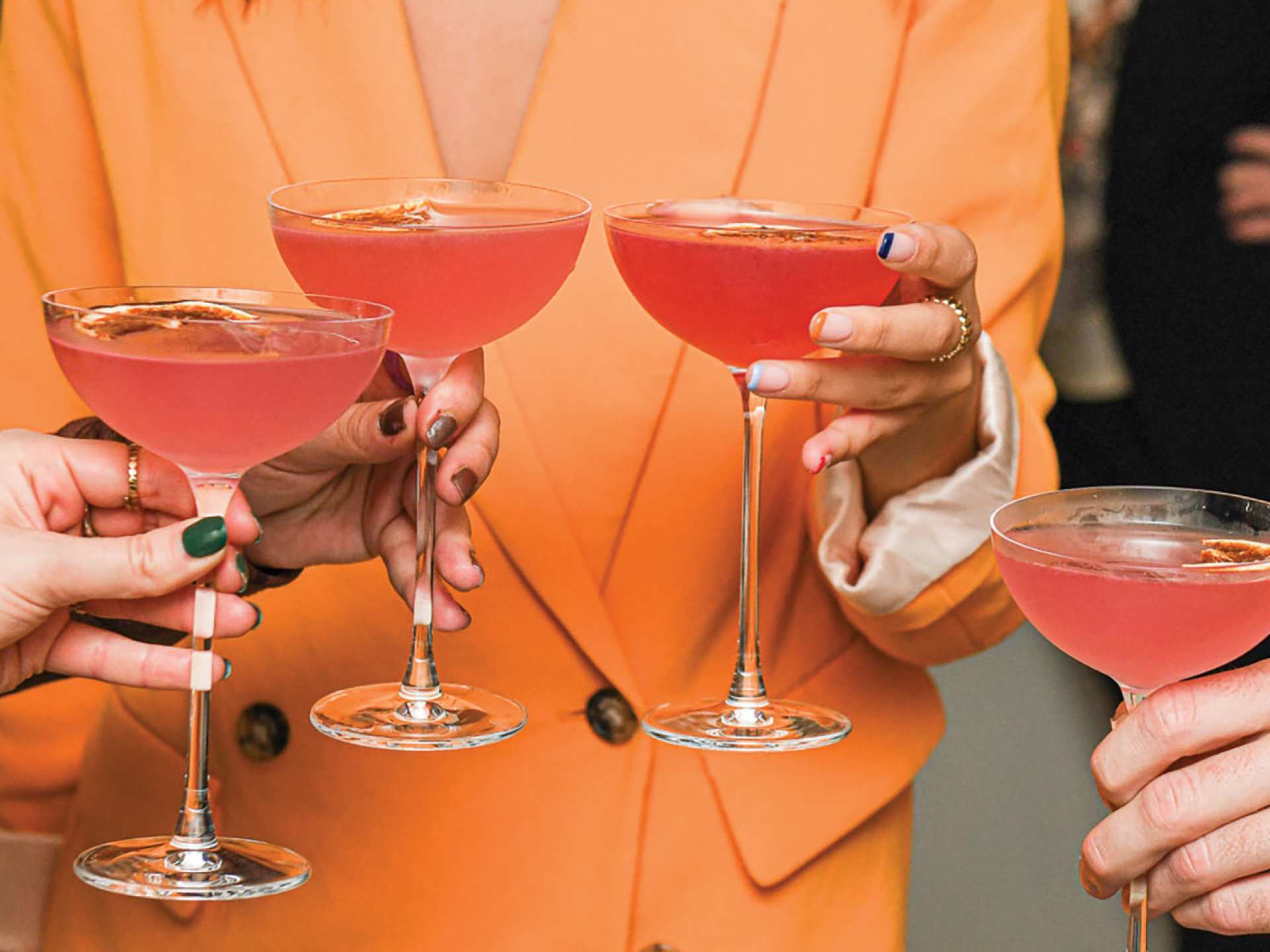 People hold cocktails in coupe glasses at Simpl Things in Toronto