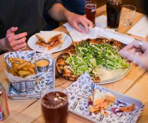 Left Field Brewery, Liberty Village, Toronto | Hands picking over an assortment of dishes at Left Field Brewery